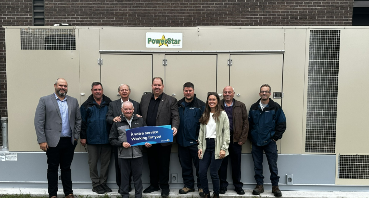 A group of people standing in front of a building, holding a rectangular sign saying 