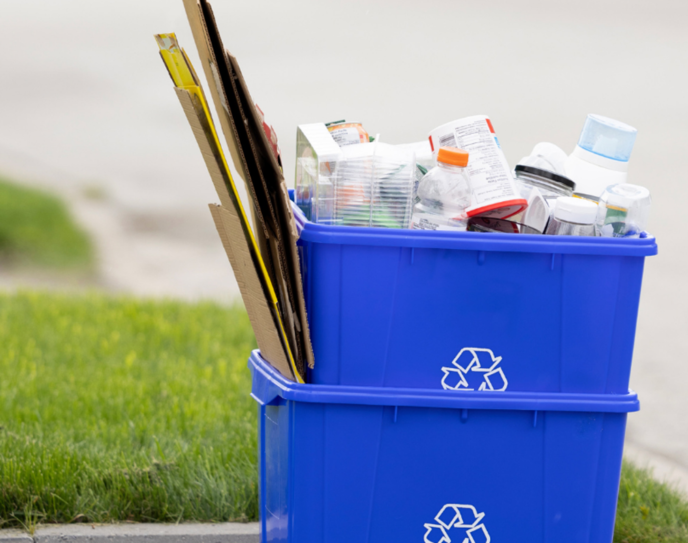 Blue recycling boxes in an entrance filled with cardboard and mixed household recycling