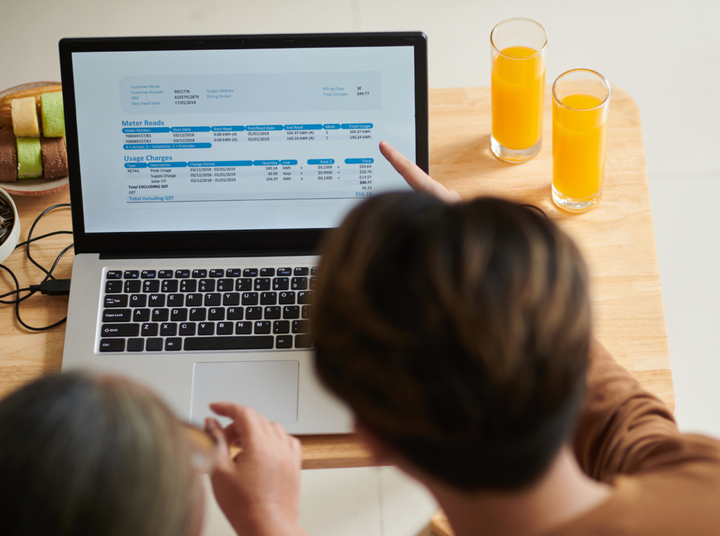 Deux personnes à une table, utilisant un ordinateur portable avec des données financières affichées à l'écran.