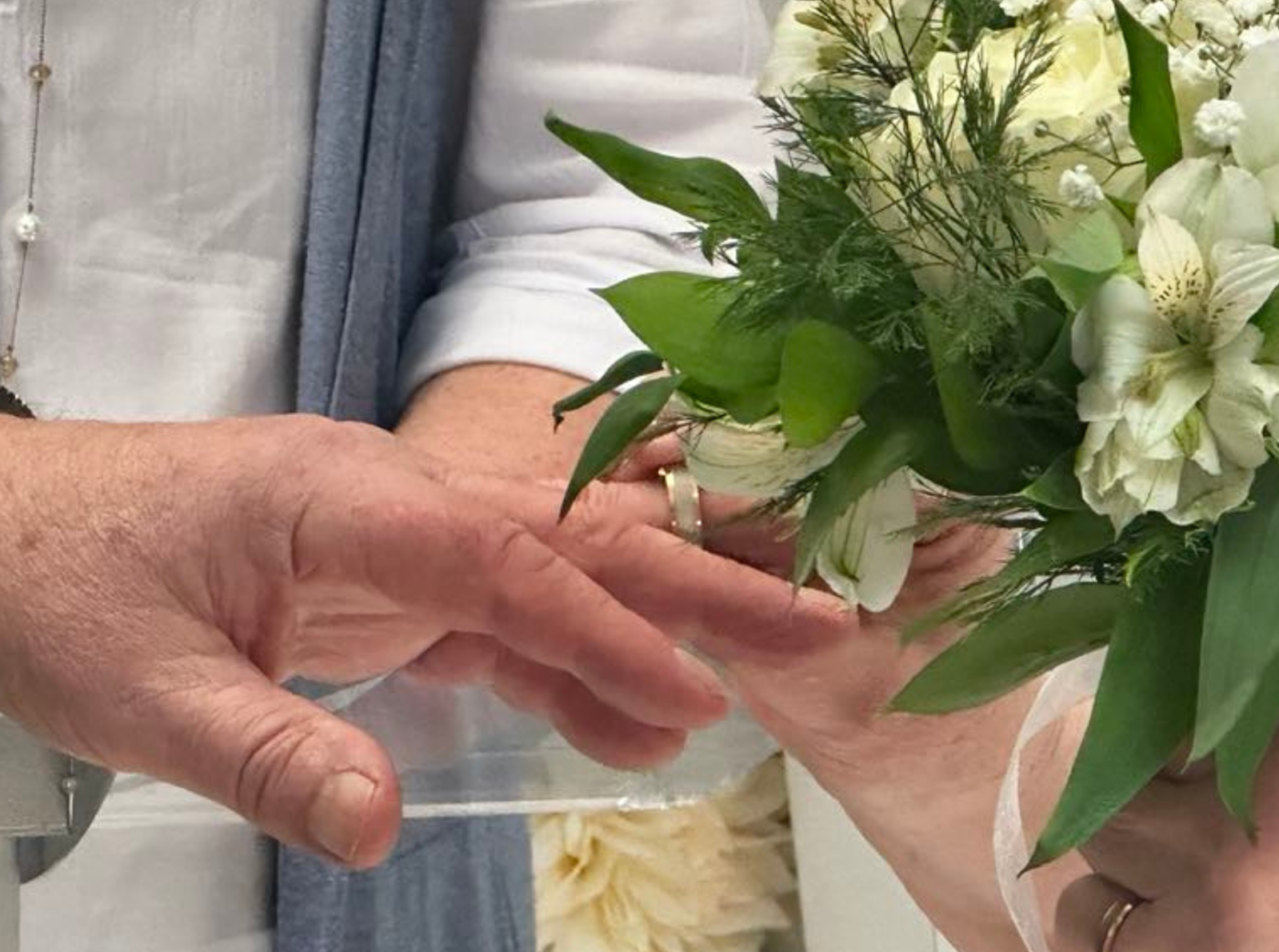 L'image montre l'échange des alliances, accompagnées d'un bouquet de fleurs blanches